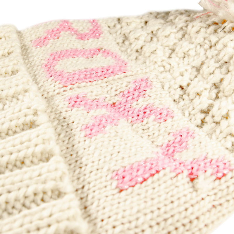 A close-up of a cream-colored knit fabric with the word LOVE stitched vertically in pink yarn, evoking the cozy winter charm of the Roxy Girls Tonic Beanie and highlighting plush, fleece-lined warmth.