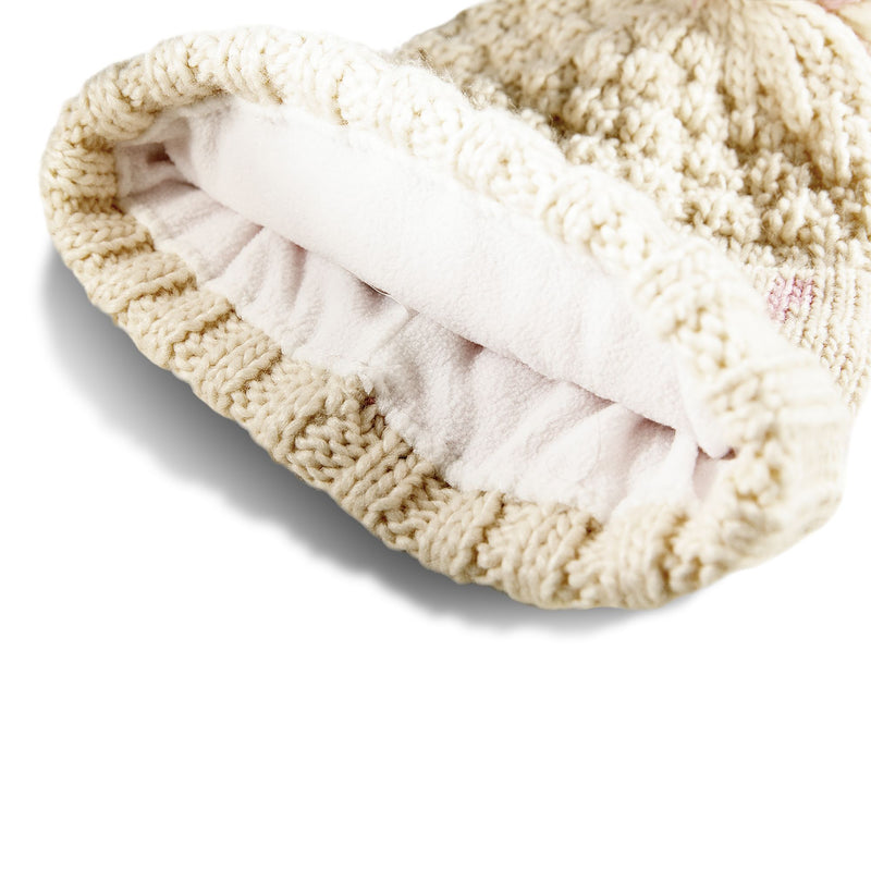Close-up of a cream-colored Roxy Girls Tonic Beanie, featuring a soft white polar fleece-lined interior and lying on its side to highlight the cozy texture—an essential winter accessory from Roxy inspired by classic style.