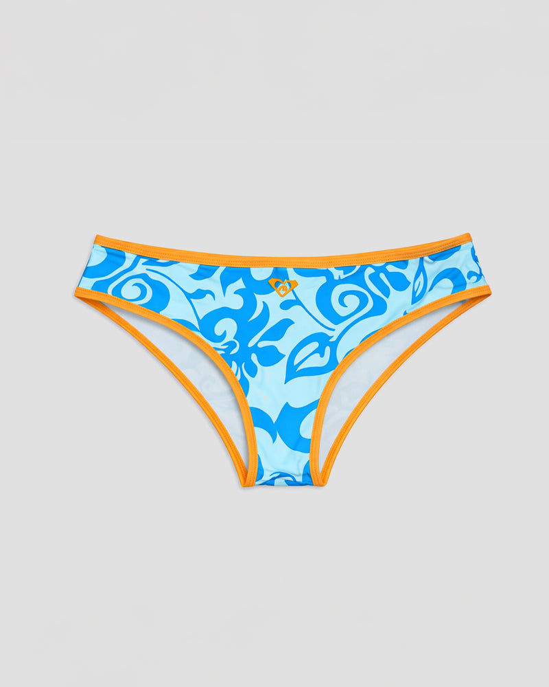 The Roxy Casey Bikini Bottom features a blue and light blue tropical print, bright orange trim, and a small yellow emblem at the front, crafted from soft swim fabric and shown on a plain light gray background.