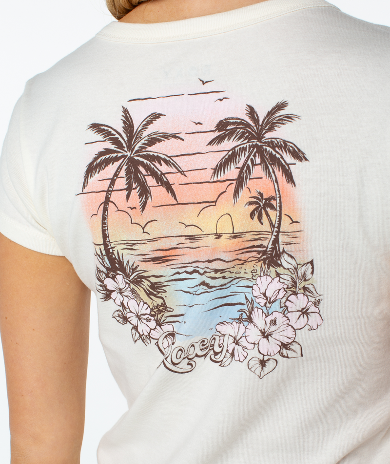 A close-up of a white, retro-inspired Kinda Salty 90S Baby Tee by Roxy featuring a colorful tropical beach sunset with palm trees, hibiscus flowers, and the word Lacey.