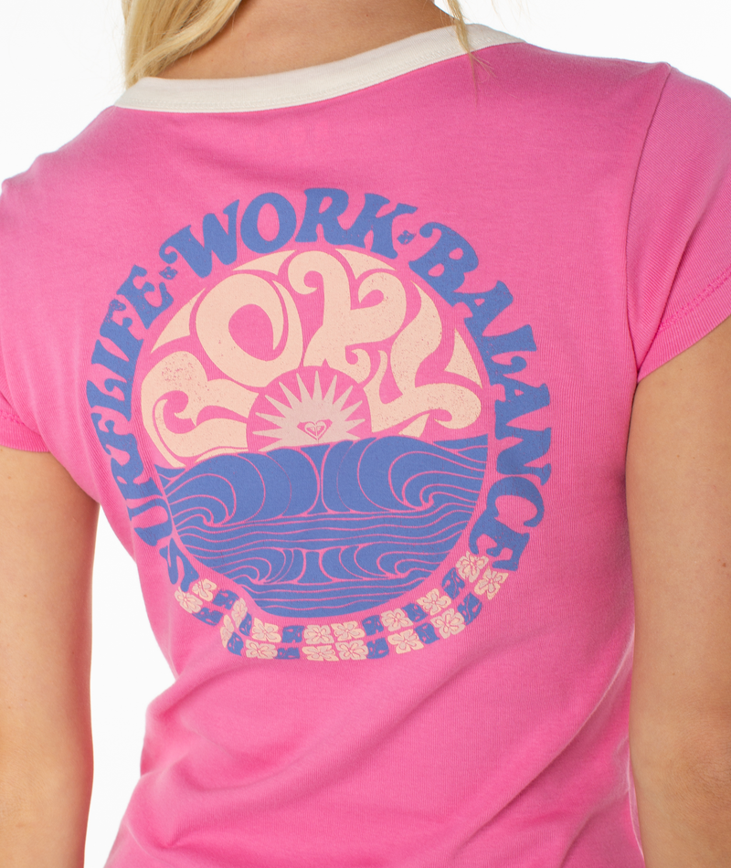 A woman wears the Roxy Surf Life 90s Baby Ringer Tee, featuring “SURF.LIFE.WORK.BALANCE” around a wave and sun graphic with bold “ROXY”—perfect for channeling retro beach vibes.