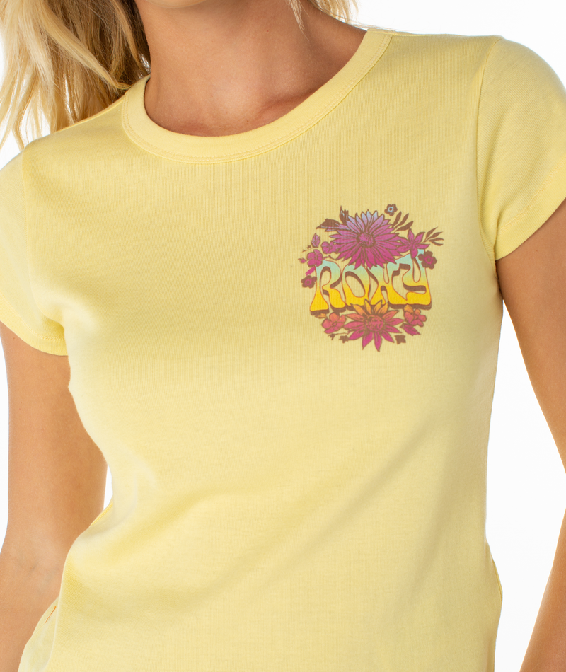 Someone wearing the ROXY Tribal Sunset 90S Baby Tee, a yellow, retro-inspired top featuring a small floral chest graphic. The beachy tee gives off vintage vibes, and the person's face is partially out of frame.
