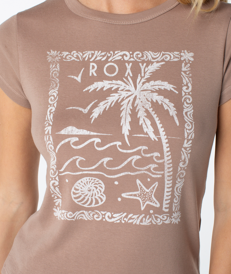 Wearing the Roxy Palm Poster 90S Baby Tee, which features a white graphic of a palm tree, waves, a shell, and a starfish with “ROXY” at the top, channels retro-inspired beachy vibes.