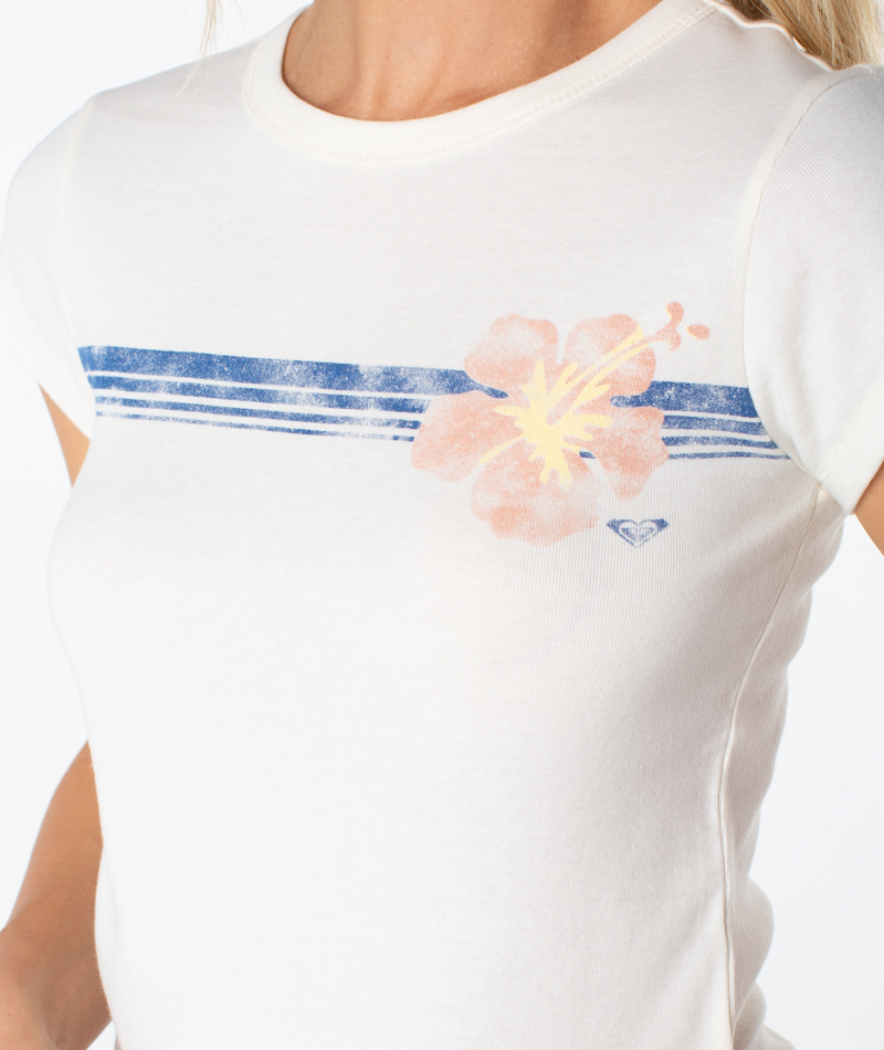A close-up of a person wearing the Roxy Swell Seekers 90S Baby Tee, featuring blue stripes and a bold pink hibiscus flower graphic for classic retro vibes.