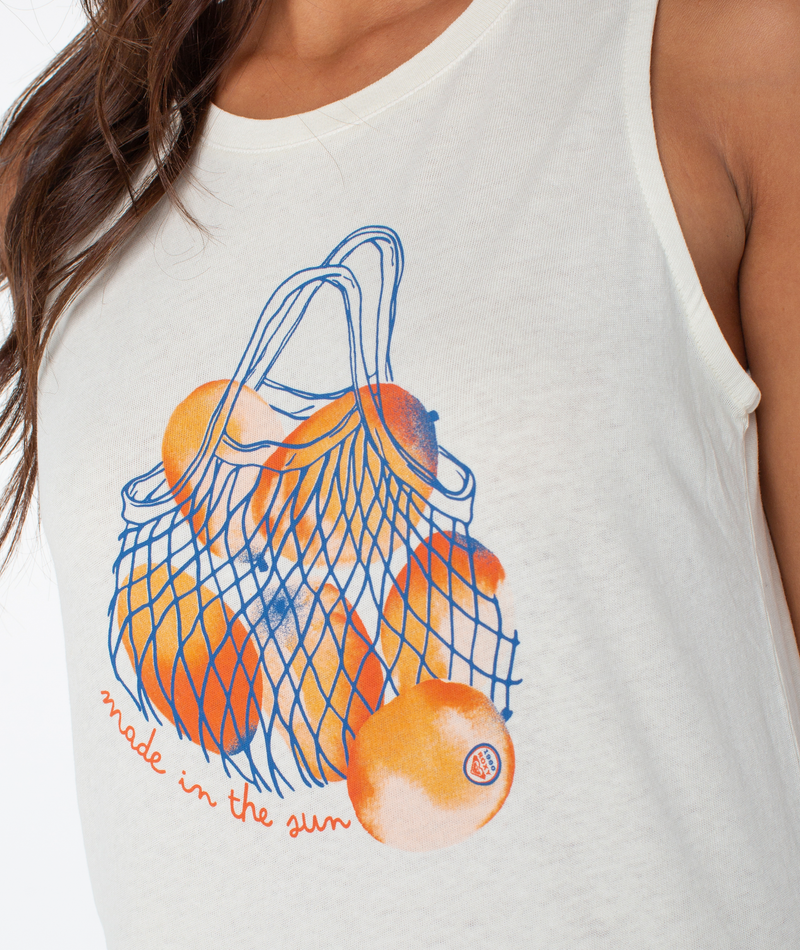 A close-up of the Roxy Made In The Sun Wildflower Midi Dress, showcasing a sleeveless white design with an orange illustration in a blue net bag and "made in the sun" in red script, adding coastal flair to your style.