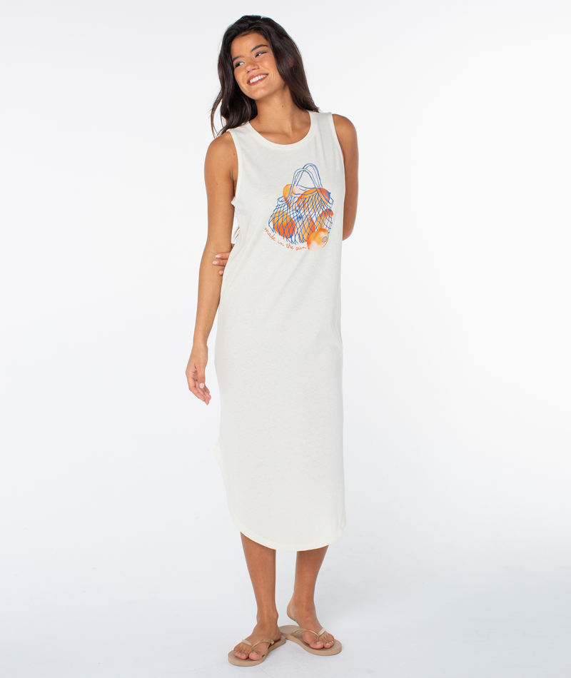 A woman in the Roxy Made In The Sun Wildflower Midi Dress, a sleeveless and breezy style with a vibrant beach bag graphic on the chest, smiles with relaxed coastal charm against a plain white background.