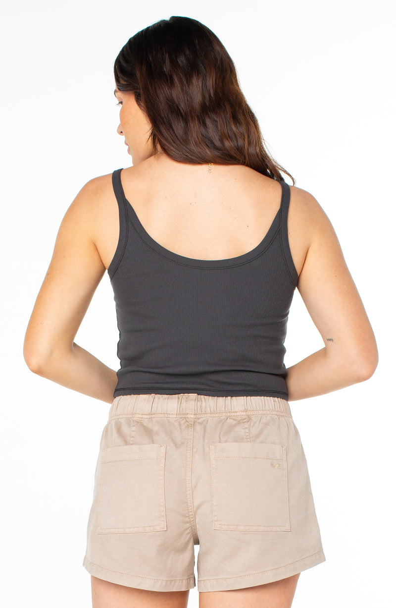 A person seen from behind wearing a charcoal grey ribbed Roxy Epic Vibe Wanderer Tank and tan shorts.