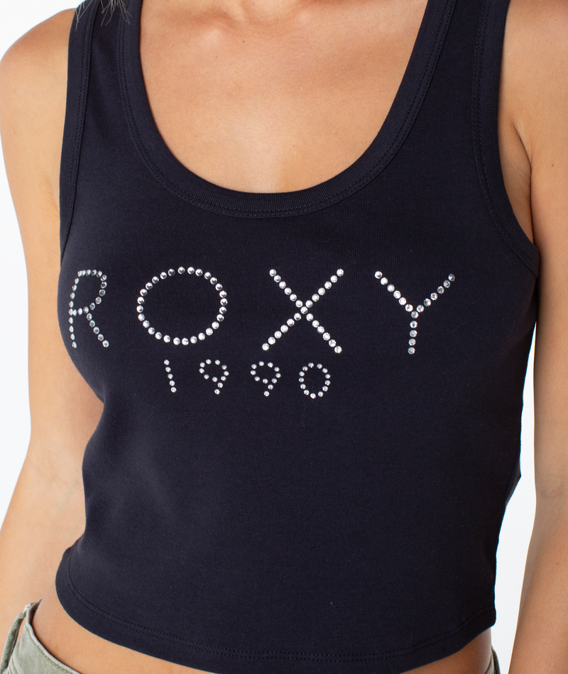 Wearing the Roxy Shine Bright Scoop Baby Rib Tank, which features “ROXY 1990” in silver studs across the front, this black crop top channels a retro-inspired 90s Baby Tee vibe.
