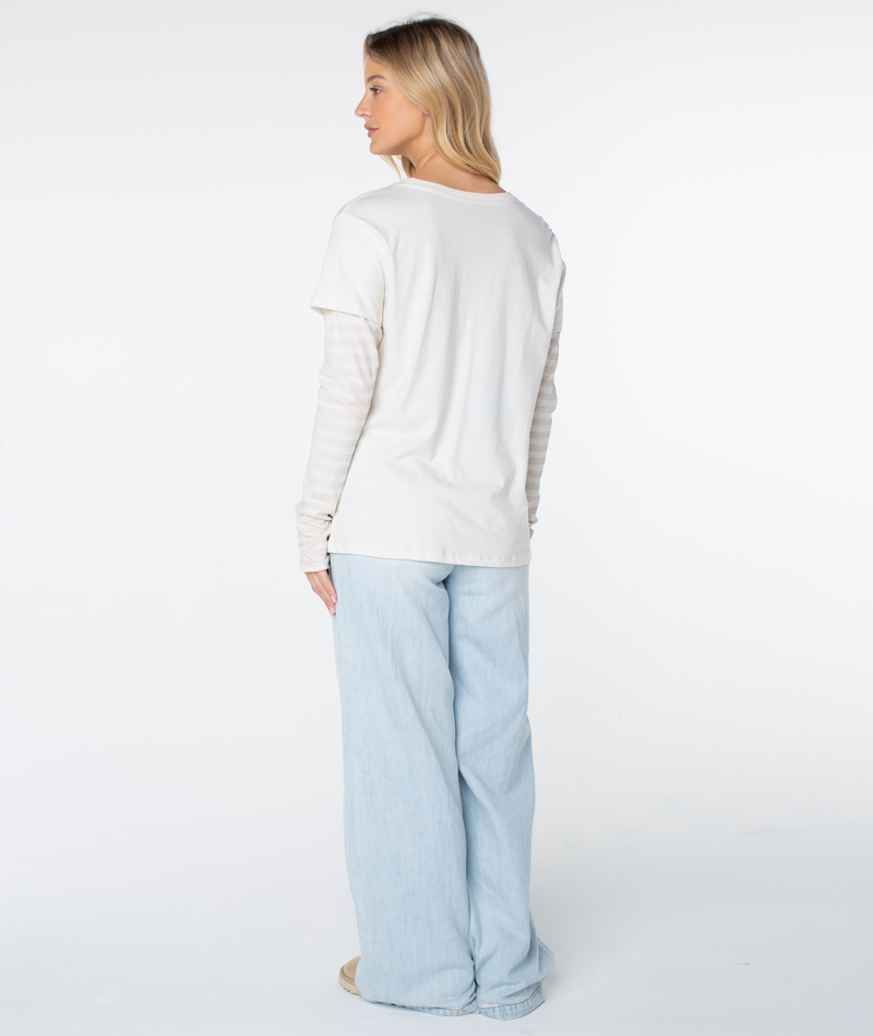 Person standing and facing away, wearing the Vintage Roxy Two-fer Top by Roxy, layered over light blue wide-leg jeans and beige shoes, against a plain white background.