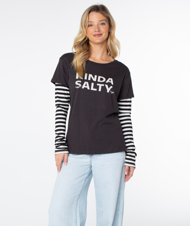 A woman in a Roxy Kinda Salty Two-fer Top and light blue jeans stands smiling against a plain white background.