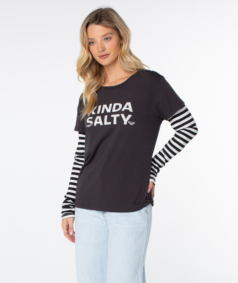 A woman with long blonde hair wears the Roxy Kinda Salty Two-fer Top and light blue jeans, posing against a white background.