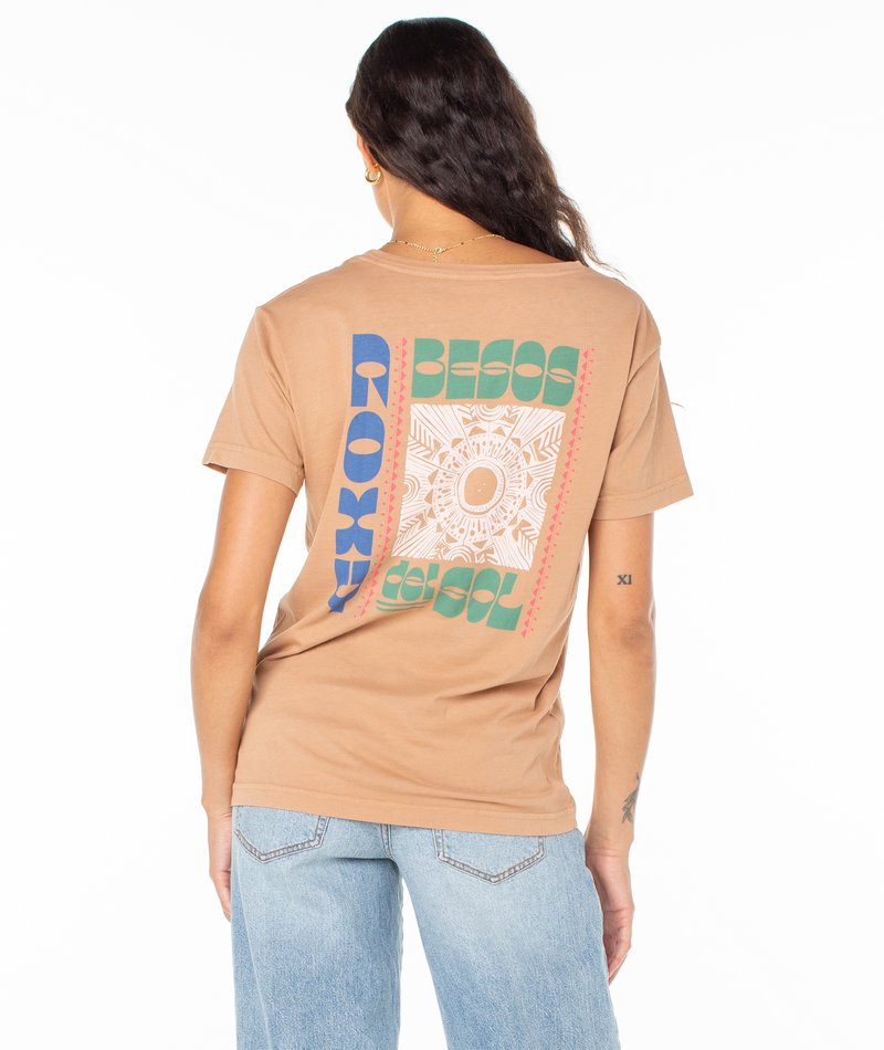 A woman wearing a tan Roxy Besos Tee featuring a colorful sun graphic on the back with the text BESOS DEL SOL.
