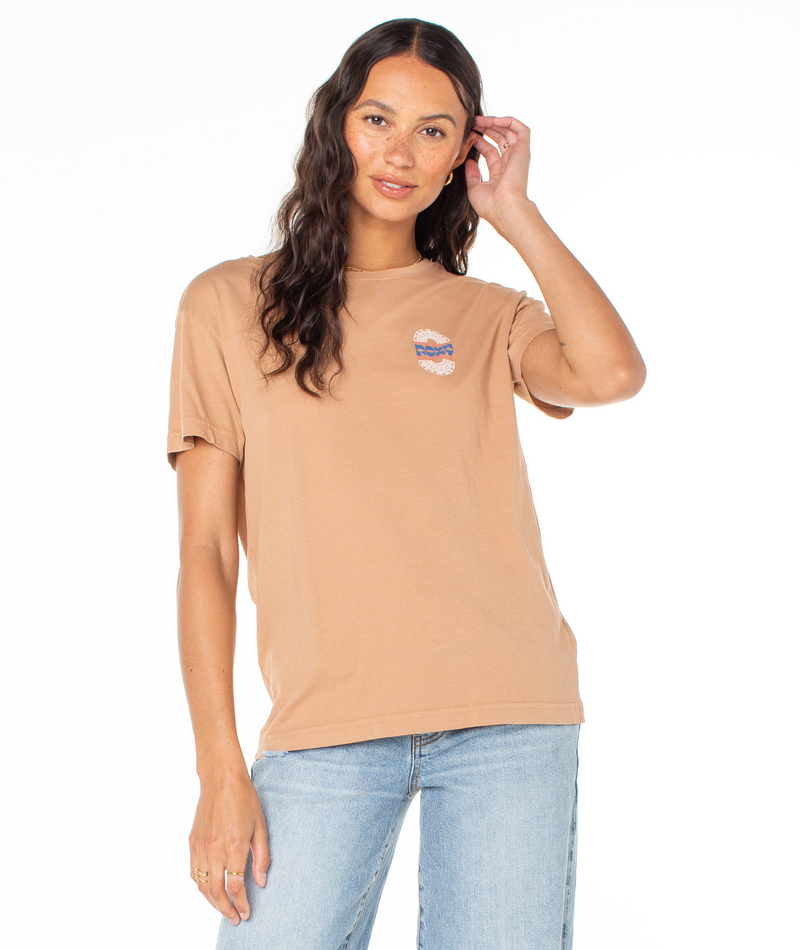 A woman wearing a tan Roxy Besos Tee with a short-sleeve silhouette and a small logo graphic on the chest.