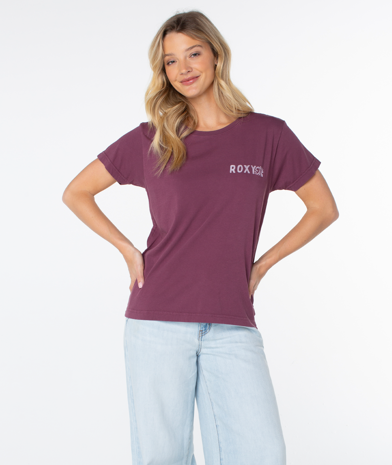 A woman wears a slouchy, dark purple Simple Palm Top with a small logo on the chest and light-wash jeans.
