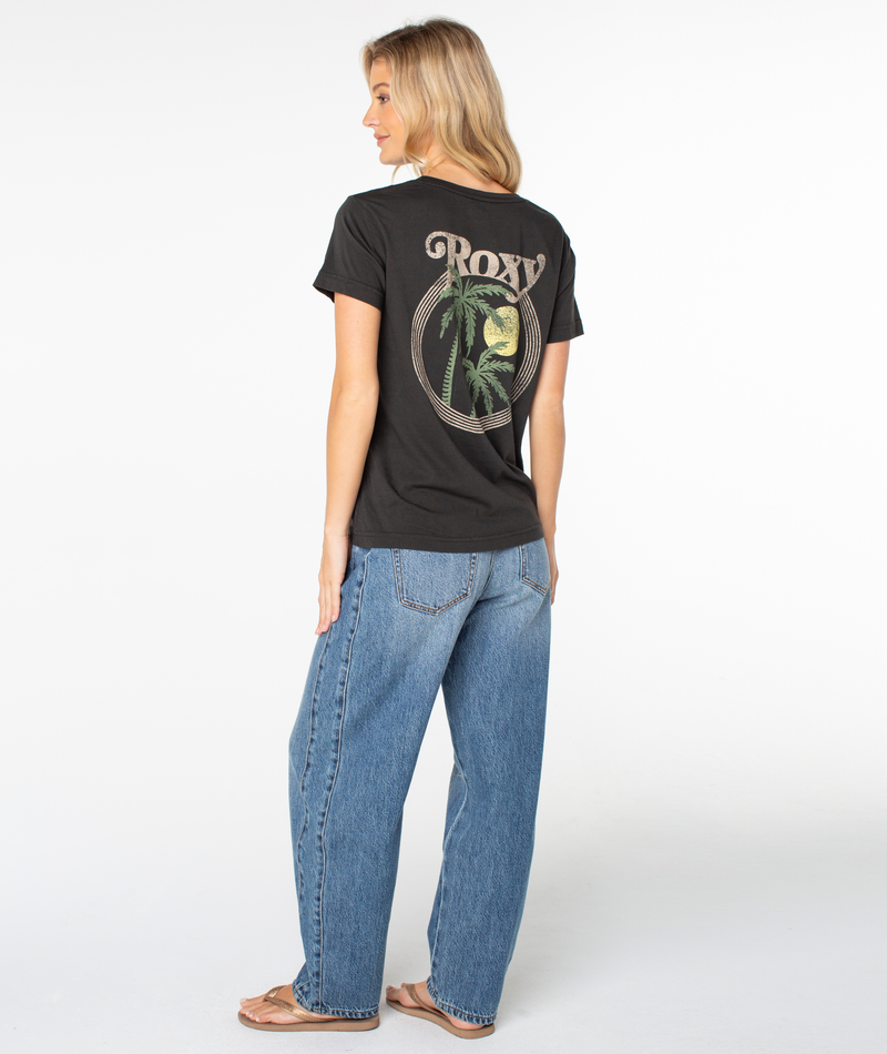 A person seen from behind wears a Roxy Palm Tree Resort Top with a black t-shirt featuring a back graphic of palm trees inside a circle and blue jeans.