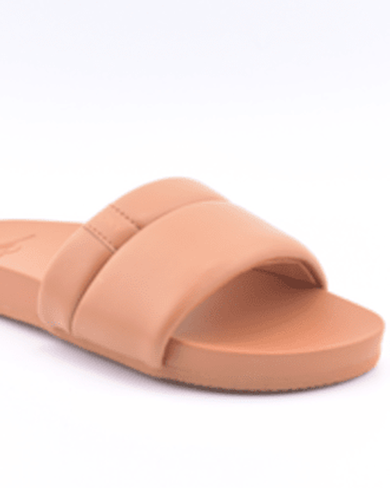 A close-up of the Roxy Slipin Slide Sandal, a tan slip-on with a wide strap, cushioned footbed, and flat sole, shown against a plain white background.