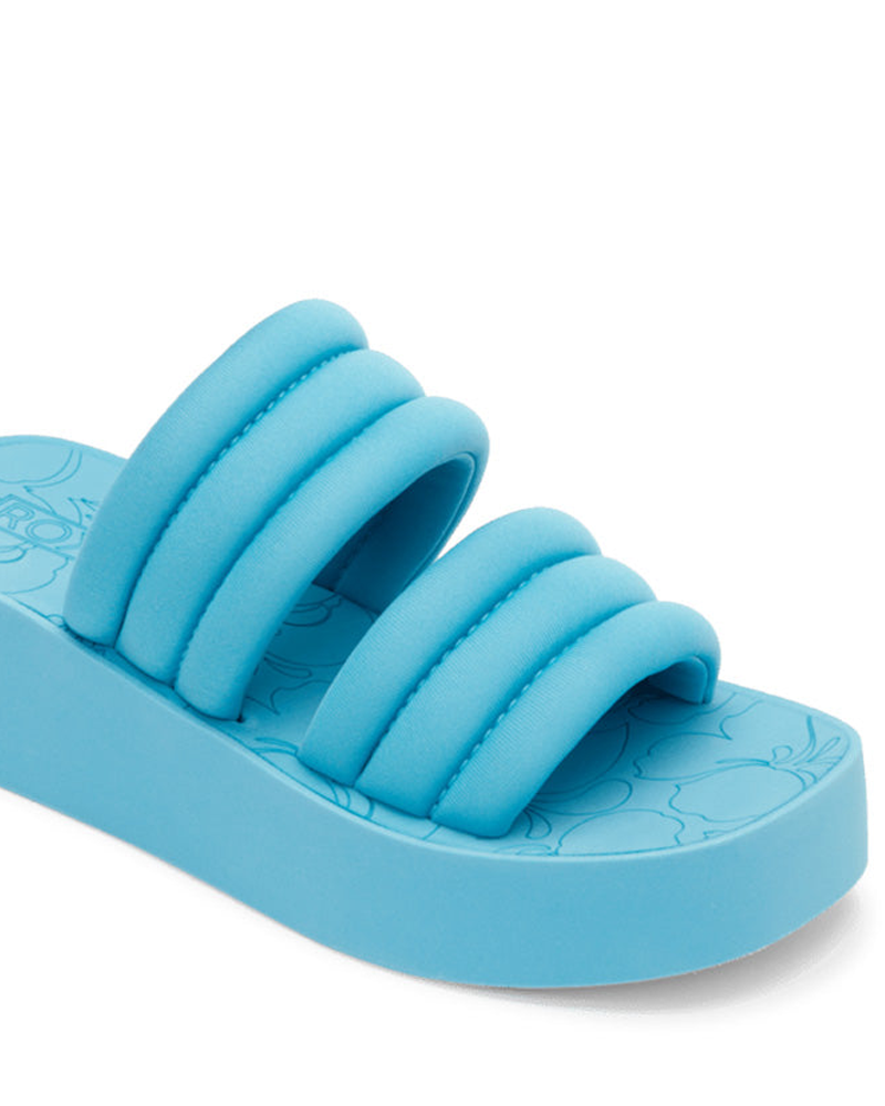 The Roxy Totally Tubular Sandal features a bright blue color, three padded straps, and a chunky platform sole. A subtle floral footbed design adds 90s-inspired flair to your beach look.