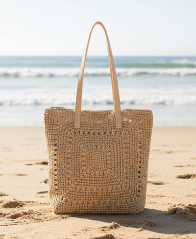 Woven bag on a sandy beach with ocean in the background