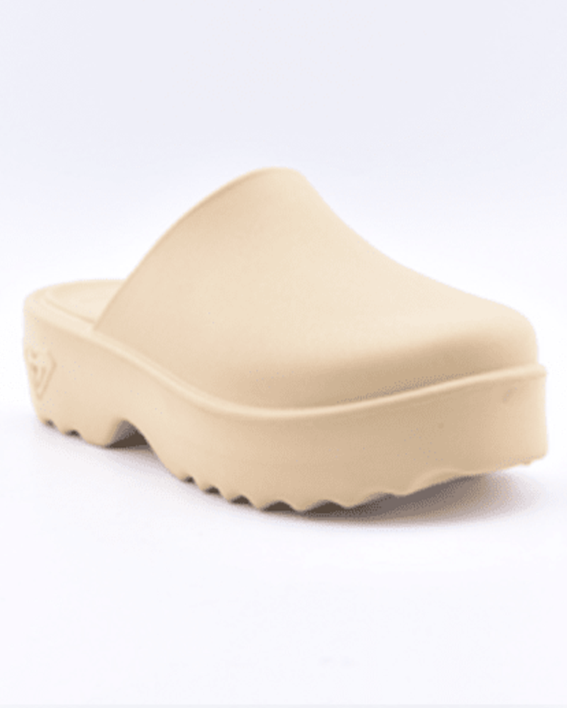 The Roxy Maddy Clog is a single beige slip-on with a thick, chunky sole, wavy tread, closed toe, and minimalist modern design.