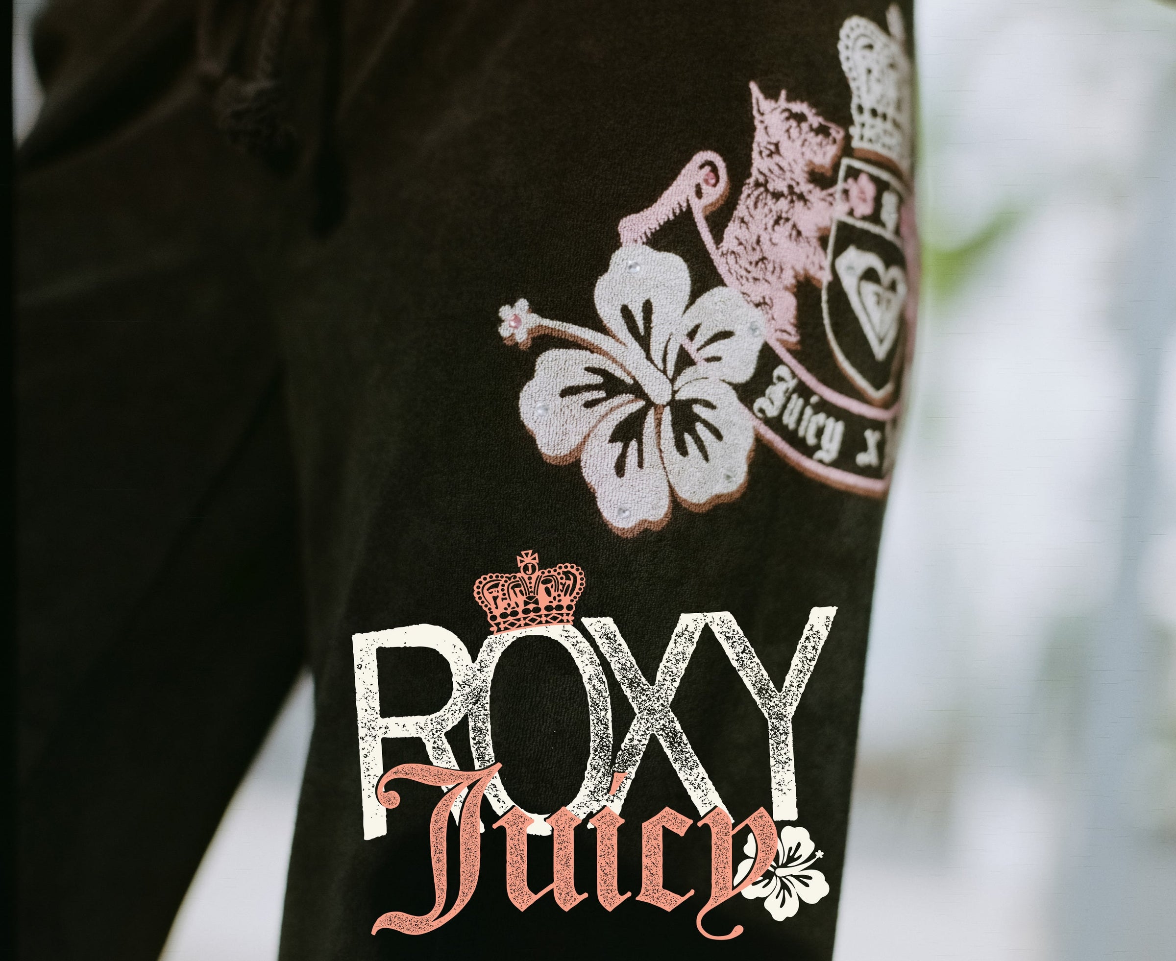 Black jacket with 'Roxy Juicy' branding and floral design on a blurred background