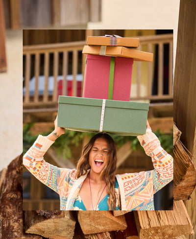 Woman holding a stack of gift boxes outdoors