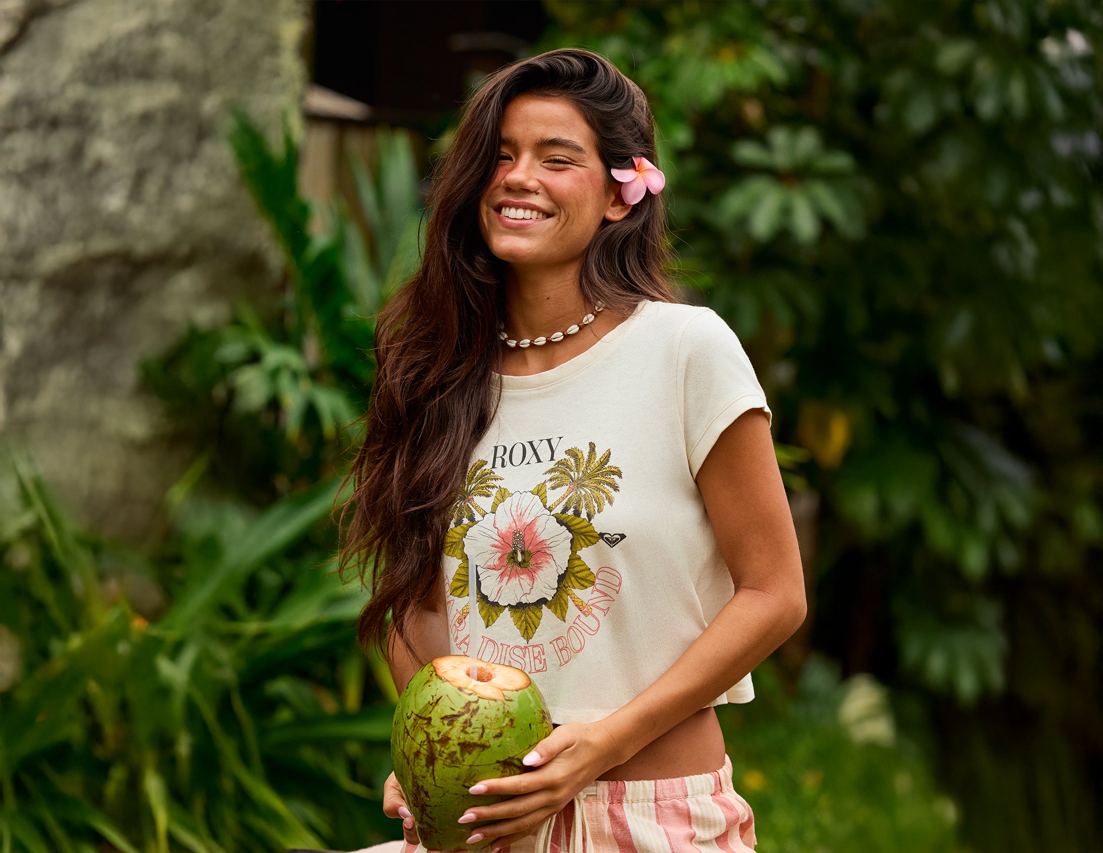 Woman holding a coconut in a tropical setting